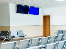 Empty seats in hospital waiting room with a television monitor.