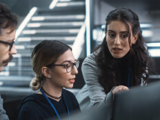 cybersecurity team members talk in front of monitors
