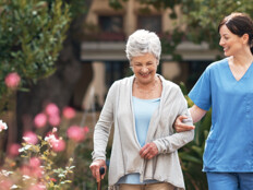 nurse walks with senior woman through a garden