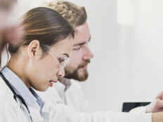 medical researchers look at data on desktop monitor