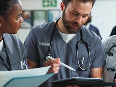 Team of clinicians talk over tablet