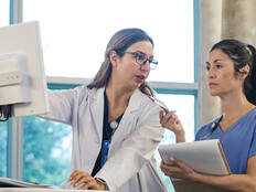 doctor shows intern AI features in an EHR on computer