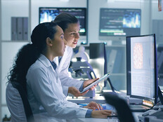 two researchers look at medical data on computer in lab