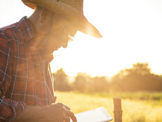 farmer on tablet in field at sunset