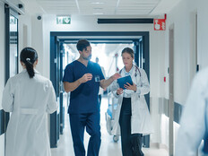 clinicians walk down busy hospital hallway