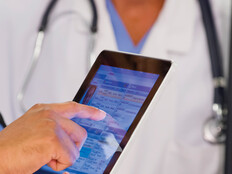 nurse and doctor look at EHR on tablet and monitor