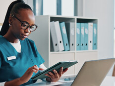 nurse using tablet and laptop at desk