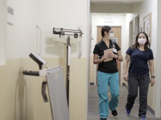 Two nurses walk through hospital hallway