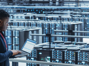 engineer with laptop overlooking data center