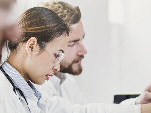 medical researchers look at data on desktop monitor