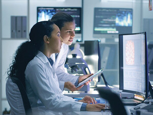 two researchers look at medical data on computer in lab