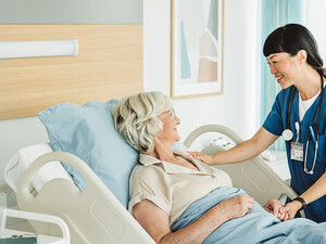 nurse cares for senior in hospital bed
