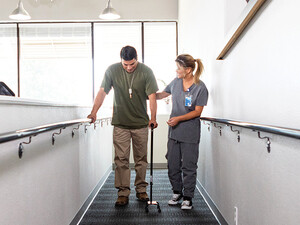 nurse helps veteran walk for rehab