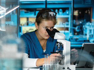 scientist looks through microscope in lab