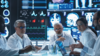 group of doctors talk amid large screens