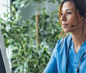 nurse monitors patients on computer - telesitting concept