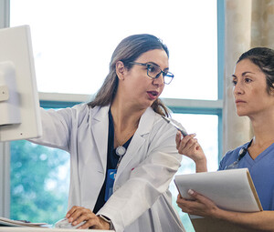 doctor shows intern AI features in an EHR on computer