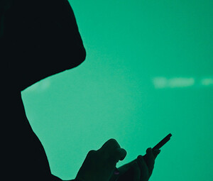 silhouette of hooded figure on phone