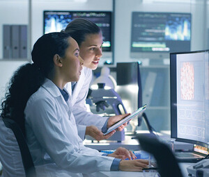 two researchers look at medical data on computer in lab