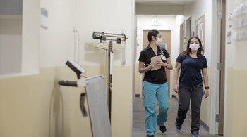 Two nurses walk through hospital hallway